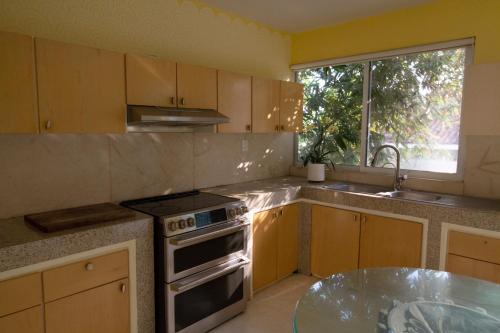 a kitchen with a stove and a sink and a window at Casita Perla Sustainable Villa with Mountain View, Long Pool, King, Grill in Texcalpan