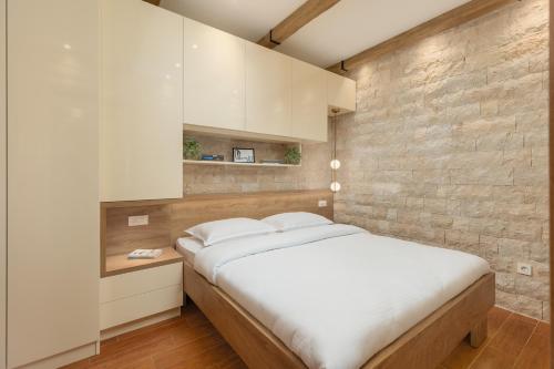 a bedroom with a large bed and a brick wall at 42° North Apartments in Tivat