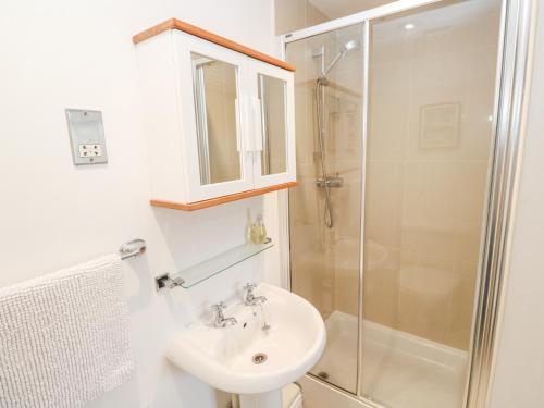 a white bathroom with a sink and a shower at 9 Headland Point in Newquay