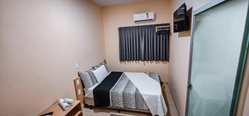 a small room with a bed and a window at Hotel Parati in Parapuã