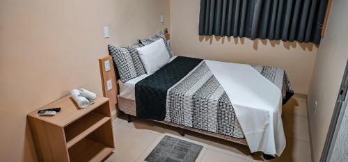 a small bedroom with a bed and a night stand at Hotel Parati in Parapuã