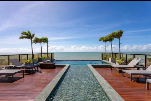 a resort infinity pool with palm trees and the ocean at Arpoar Flat 118 - De frente para o mar in João Pessoa