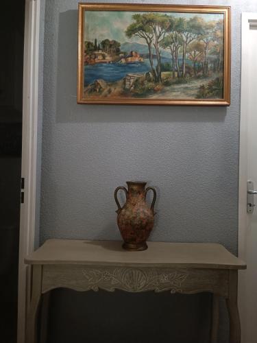un vase assis sur une table sous un tableau dans l'établissement Chambre d'hôtes petit déjeuner compris, à Carcassonne