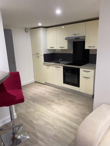 une cuisine avec des placards blancs et une chaise rouge dans l'établissement Joli appartement, à Aytré