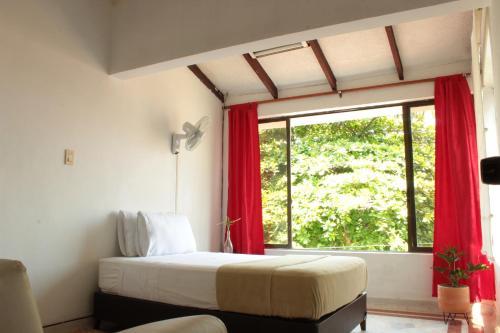a bedroom with a bed with red curtains and a window at Timeless Oasis Hostel in Cali
