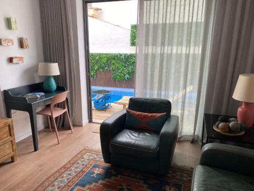 a living room with a chair and a desk and a window at Casa ancora azul Fuseta in Fuzeta