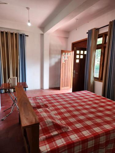 a bedroom with a bed and a table and a door at Silvil Homestay in Bandarawela
