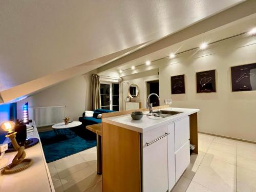 a kitchen with a sink and a living room at Pit & Lodge in Malmedy