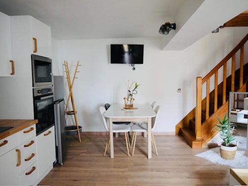 une salle à manger avec une table et une cuisine avec des escaliers dans l'établissement Les chants d'oiseaux, à Chaumont-sur-Loire