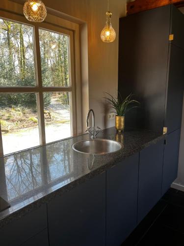 a kitchen counter with a sink and a window at Guesthouse Oeyenbos in Knegsel