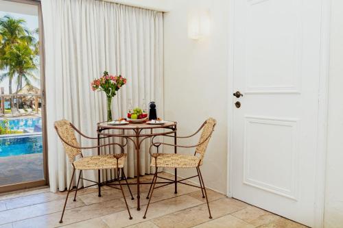 a table with chairs and a vase of flowers on it at Camino Real Zaashila Huatulco in Santa Cruz Huatulco