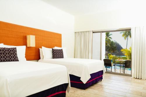 a hotel room with two beds and a balcony at Camino Real Zaashila Huatulco in Santa Cruz Huatulco
