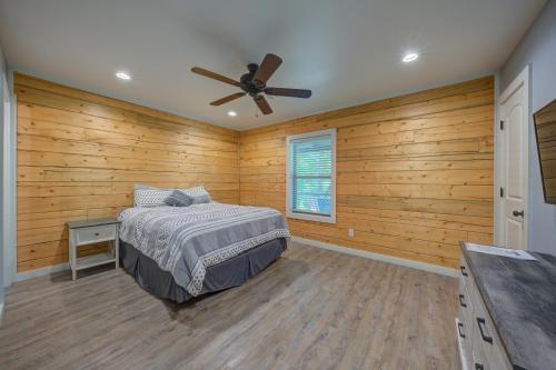 a bedroom with wooden walls and a bed and a ceiling fan at Happy Times on Caddo River by StayLage in Glenwood
