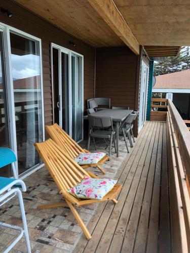 a wooden deck with a table and chairs on it at Cabañas brisas del mar Family in Los Molles