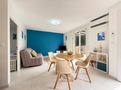 un salon avec une table et des chaises et un mur bleu dans l'établissement Splendide - Piscine - Plage 500m, à Carqueiranne