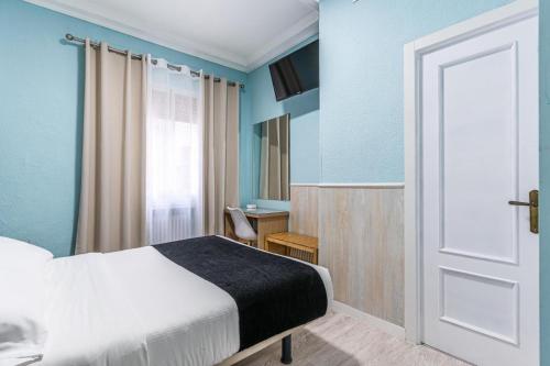 a bedroom with a bed and a window and a door at Hotel Mexico in Madrid