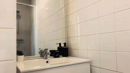 La salle de bains est pourvue de carrelage blanc, d'un lavabo et d'un miroir. dans l'établissement Le Distingué Central - Gare, à Mâcon