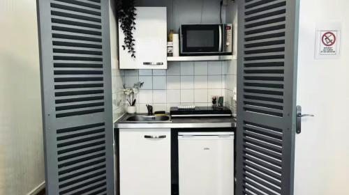 une petite cuisine avec des armoires blanches et un micro-ondes dans l'établissement Le Distingué Central - Gare, à Mâcon