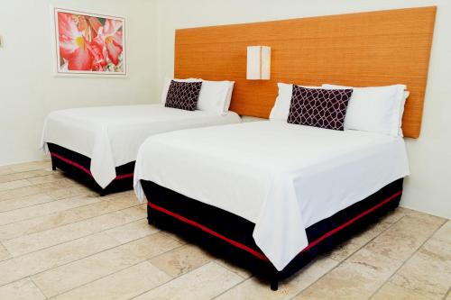 two beds in a hotel room with white sheets at Camino Real Zaashila Huatulco in Santa Cruz Huatulco