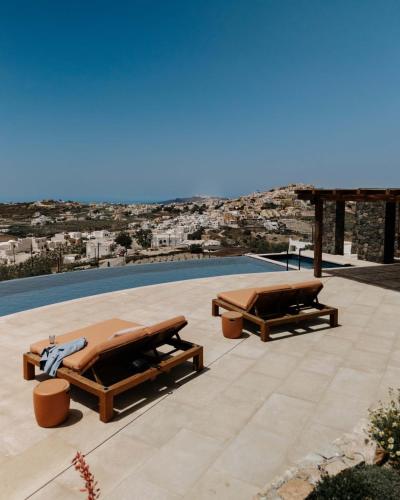 two wooden benches sitting on a patio near a pool at Patina Vivera Estate Santorini in Pirgos