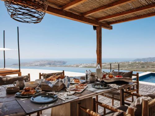 a table with food and a view of the ocean at Patina Vivera Estate Santorini in Pirgos