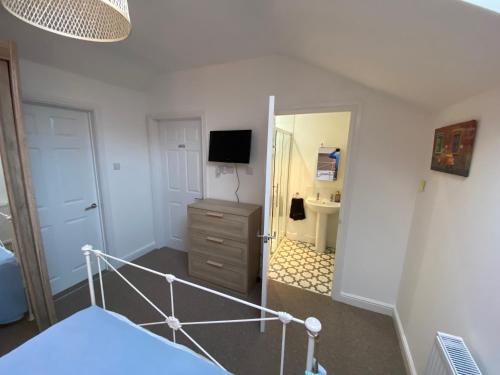 a bedroom with a bed and a dresser with a television at Bucklands in Nailsea
