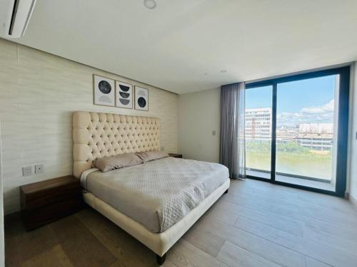 Un dormitorio con una cama grande y una ventana grande. en Elegante depa vista al malecón y mar by G P S rentas, en Mazatlán