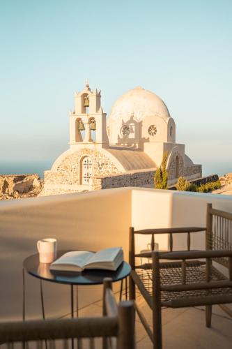 a table with a book and a cup of coffee and a church at Patina Vivera Estate Santorini in Pirgos
