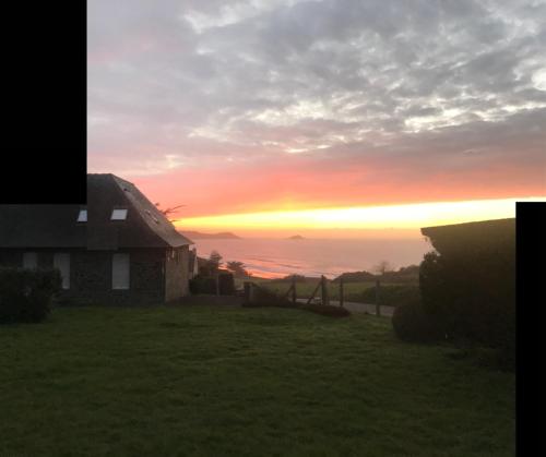 une maison sur une colline avec un coucher de soleil en arrière-plan dans l'établissement Face à la mer, à Erquy
