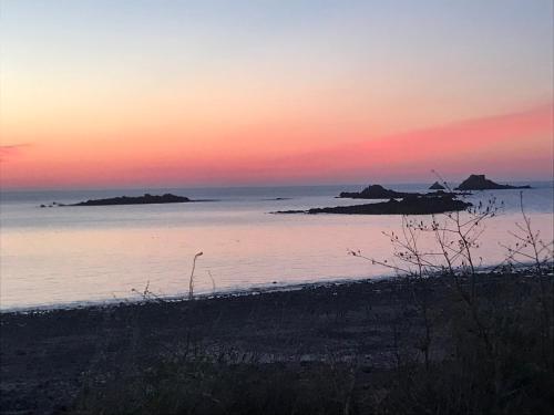 un coucher de soleil sur l'eau avec des îles au loin dans l'établissement Face à la mer, à Erquy