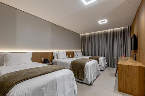 a hotel room with two beds and a television at Amazon Aeroporto Hotel in Cuiabá