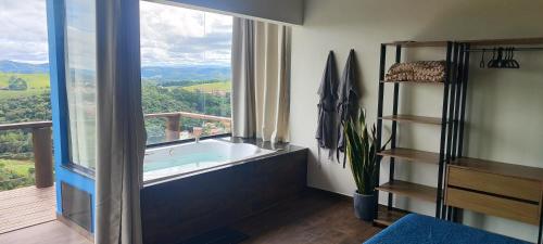 a bathroom with a tub and a large window at Chalés Vista da Serra in Cunha