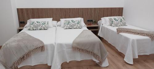 two beds with white blankets and pillows in a room at PILGRIMSROOM la Parada Del Camino in Negreira