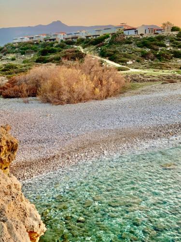 a rocky beach with water and buildings in the background at Boho Bay Apartment in Akanthou