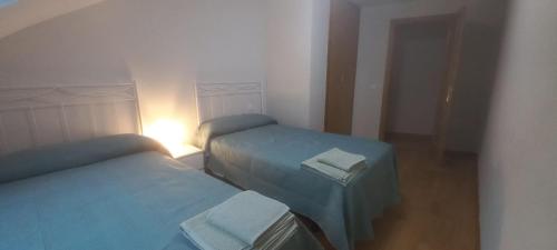 due letti in una piccola camera da letto con luce accesa di Ático con 3 dormitorios y garaje a 15 minutos de Valladolid a Tudela de Duero