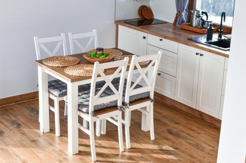 a white kitchen with a table and chairs at Aleksandrówka in Szlembark