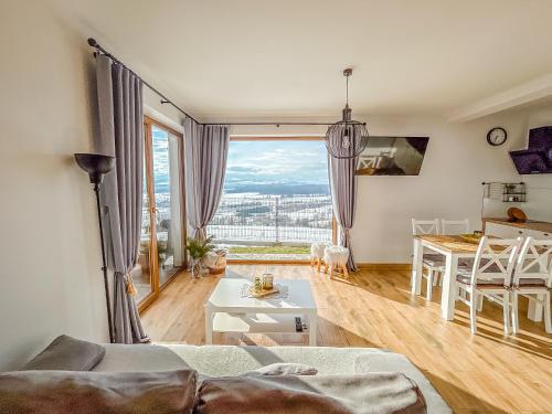 a living room with a large window and a table at Aleksandrówka in Szlembark
