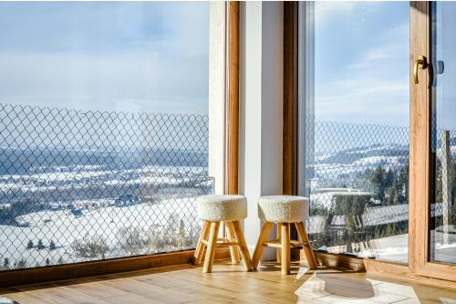 two stools in front of a window with a view at Aleksandrówka in Szlembark