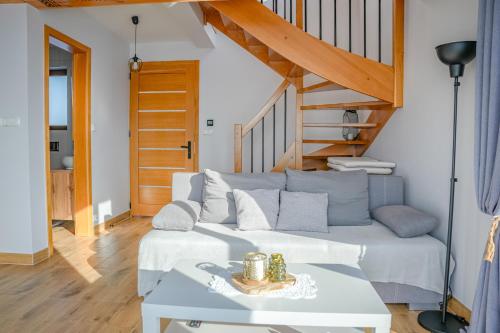 a living room with a white couch and stairs at Aleksandrówka in Szlembark