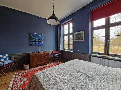 a bedroom with blue walls and a bed and windows at Ferienhaus in Steffenshagen mit Terrasse in Steffenshagen