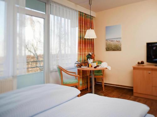 a bedroom with a table and a bed and a window at Appartements im Freizeitpark Weissenhäuser Strand in Weissenhäuser Strand