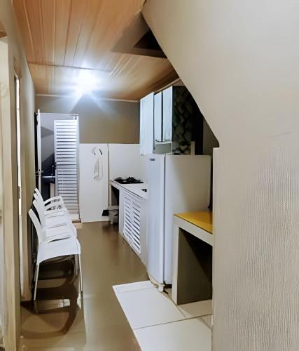 a kitchen with a white refrigerator and white chairs at Temporada no Atalaia in Salinópolis