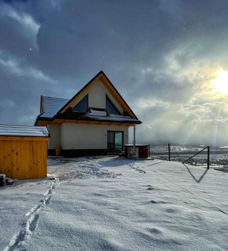 a house in the snow with the sun behind it at Aleksandrówka in Szlembark
