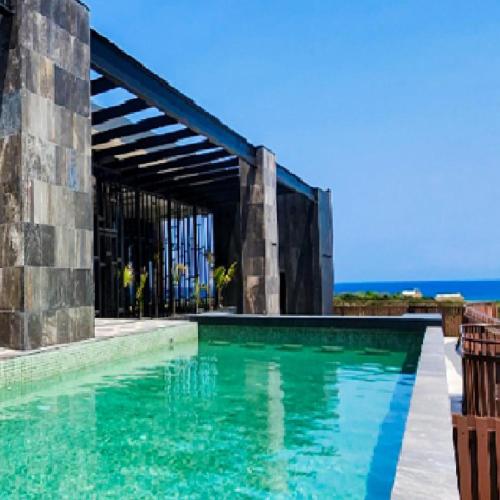 a swimming pool with turquoise water in front of a building at Seascape apartment near the beach with a sea-view rooftop and infinity pool in Tulum