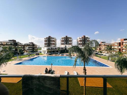 a swimming pool with a palm tree and some buildings at Luxury studio, Iskele, Cyprus in Iskele