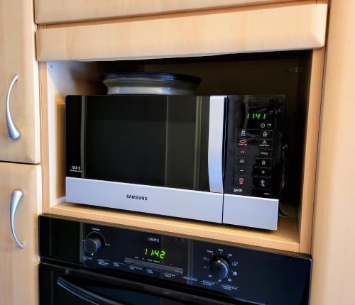 d'un four micro-ondes dans une armoire en bois. dans l'établissement L' Appart BELLE VUE GARE ET CENTRE 10 mn à pied GARAGE GRATUIT, à Colmar