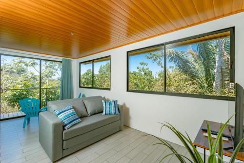 a living room with a couch and some windows at Tardes Doradas in Quepos