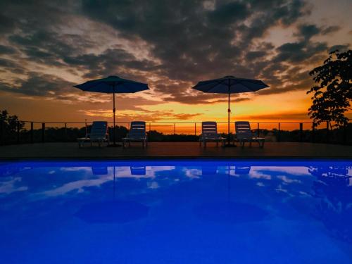 two chairs and umbrellas sitting next to a swimming pool at Tardes Doradas in Quepos