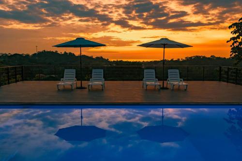 a group of chairs and umbrellas and a pool with a sunset at Tardes Doradas in Quepos