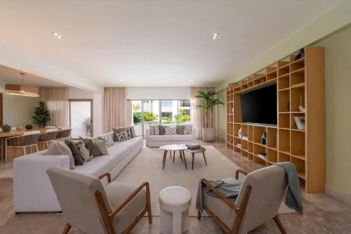 a living room with a couch and a tv at La Amada Residences Private Beach Getaway with Pools & Gym in Cancún
